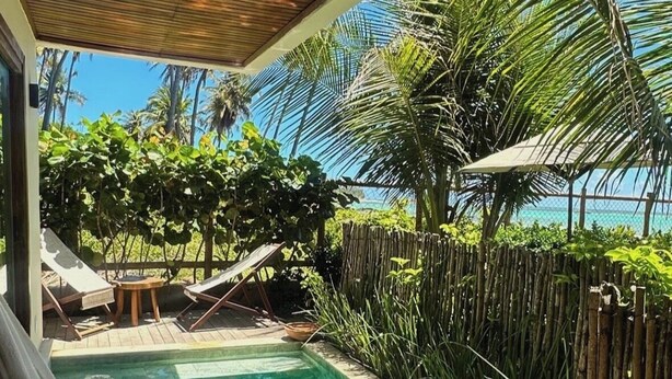 Une piscine à l’eau claire, entourée d’une végétation luxuriante et dotée d’une terrasse en bois.