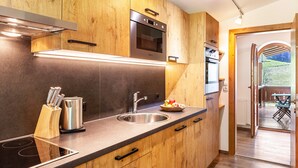 Una cocina moderna con armarios de madera, electrodomésticos de acero inoxidable y vistas a un patio exterior.