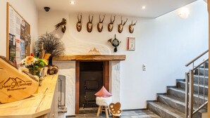 Un vestíbulo de hotel con un mostrador de recepción de madera, una chimenea, decoración de pared con astas y una escalera.
