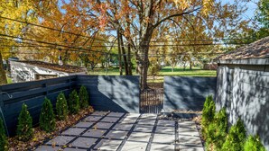 A paved patio area with a stone pathway, surrounded by a low wall and small evergreen shrubs. - Modern Zen Farmhouse to help you recharge and rejuvenated (Royal Oak)