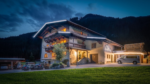 Ein mehrstöckiges Hotel mit Balkonen, einer Garage und einer Bergkulisse.