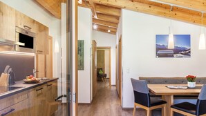 Een moderne keuken met houten kastjes, een inbouwoven en een eethoek met een houten tafel en stoelen.