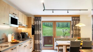 Een moderne keuken met houten kastjes, een inbouwoven en een eethoek met een tafel en stoelen.