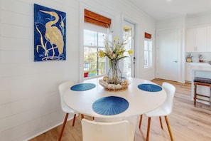 Enjoy meals in this dining area with a round table for four, surrounded by a vase with flowers and a decorative painting.