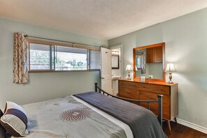 A bedroom with a bed, dresser, and window with blinds.