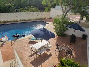 Ein Schwimmbecken mit Luftspielzeug, einem Tisch und Stühlen sowie Sonnenschirmen.