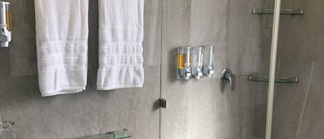 Ein modernes Badezimmer mit Duschkabine aus Glas, Toilette und Waschbecken mit Seifenspender.