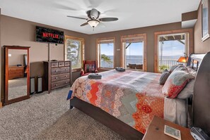 A bedroom with a bed, dresser, TV, and a view of the outdoors. - Stone Ledge Refuge with Hot Tub and Gorgeous Views (Rising Fawn)