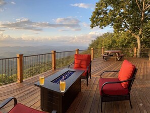 Une terrasse avec un foyer intégré, des chaises rouges et une vue sur les montagnes.