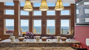 A kitchen with a granite countertop, wooden cabinets, and a large window with a view of the sea. - Stone Ledge Refuge with Hot Tub and Gorgeous Views (Rising Fawn)