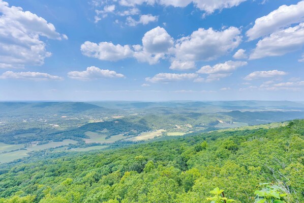A panoramic view of a lush, green landscape with rolling hills and a clear blue sky.