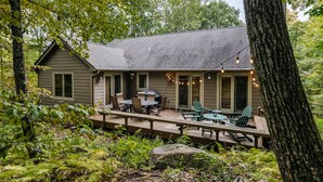 A cabin with a deck, outdoor seating, and string lights. - Welcome to our stunning 3-bedroom, 2-bathroom house nestled in the heart of Wintergreen, Virginia. (Wintergreen Resort)