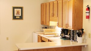 A kitchen with wooden cabinets, a white countertop, and two pendant lights. - Stones Throw from Giant City Park, Wineries, Hiking, Biking, Hunting and more. (Makanda)