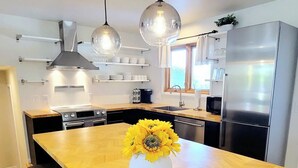 A modern kitchen with a central island, stainless steel appliances, pendant lighting, and a view of the outdoors. - $0 Fees-Hot Tub, Lake View Oasis-Near Shops/Dining (Arvada)