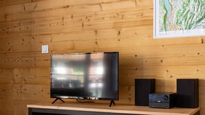 Una sala de estar moderna con una pared de madera, un televisor de pantalla plana, dos altavoces y un mapa en la pared.