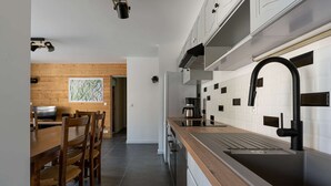 Una cocina moderna con una mesa y sillas de madera, un grifo negro y salpicadero de azulejos blancos.