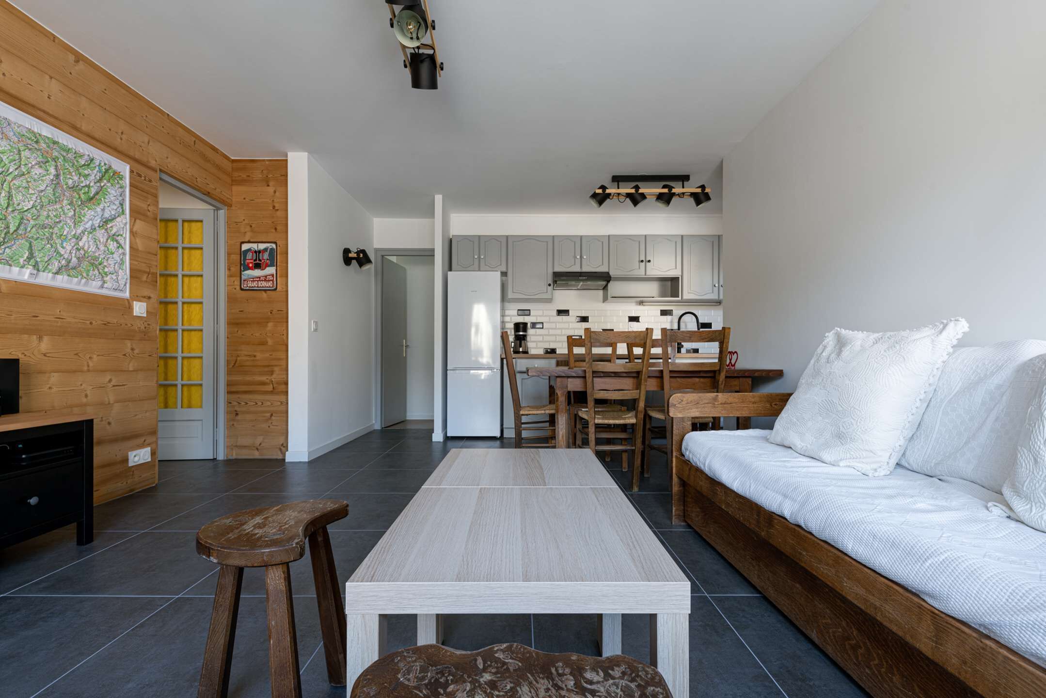 Ein modernes Wohnzimmer mit Holzboden, einem weißen Sofa, einem Couchtisch aus Holz und einem Fernseher auf einer Holzkommode.