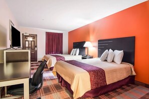 Et hotelværelse med to senge, et skrivebord, et fjernsyn og en lampe.