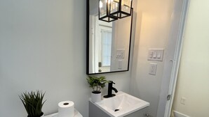 A modern bathroom with a white toilet, a white sink, and a mirror above the sink.