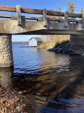 Un pont de pierre enjambe une rivière paisible, et une passerelle en bois permet de la traverser.