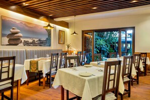 A restaurant with wooden flooring, white tablecloths, and a painting of rocks on the wall. - Sterling Park Kalimpong (Kalimpong)