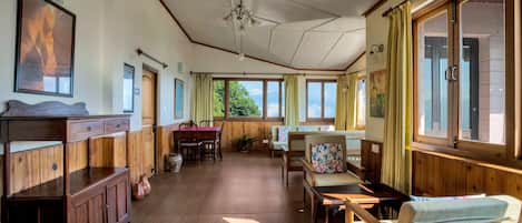 Una habitación amplia con paneles de madera, un comedor y grandes ventanales con vistas al exterior.