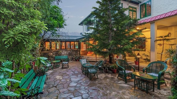 A courtyard with stone flooring, green furniture, and potted plants. - Sterling Park Kalimpong (Kalimpong)