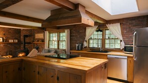 Une cuisine avec des meubles de rangement en bois, une cuisinière encastrée et une grande fenêtre avec des rideaux.