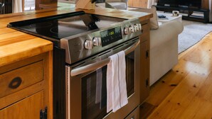 Une cuisine moderne dotée d’une cuisinière en acier inoxydable, de meubles en bois et d’une grande fenêtre.