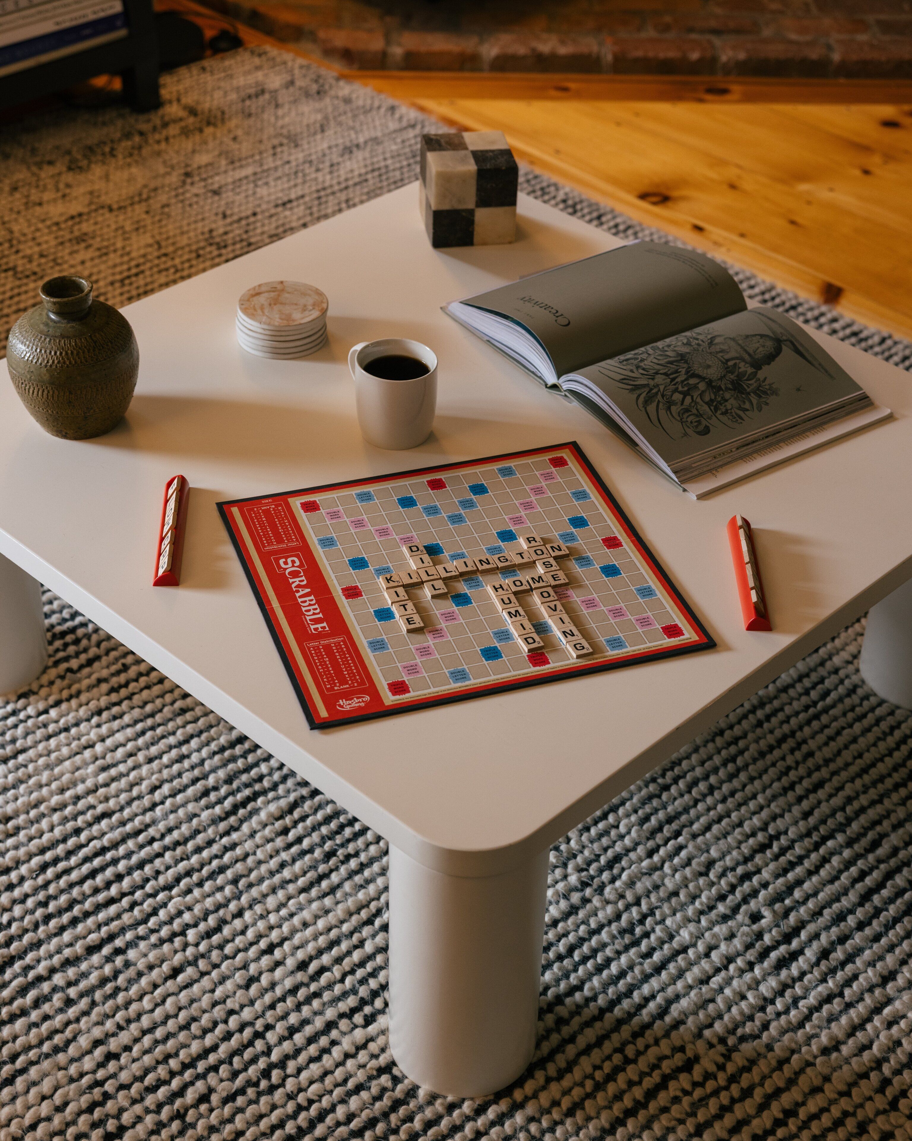 Un jeu de société, une tasse, un livre et un petit cube sur une table.