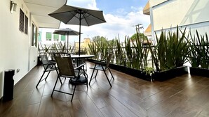 An outdoor patio with a table and chairs, surrounded by potted plants. - La Casa del Reloj - Zona de Hospitales (Mexico City)