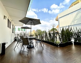 Un patio al aire libre con una mesa y sillas, rodeado de plantas en macetas.