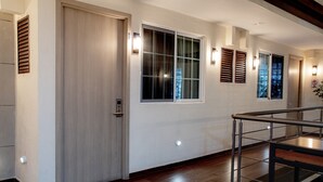 A hallway with wooden flooring, a glass railing, and a door with a handle. - La Casa del Reloj - Zona de Hospitales (Mexico City)