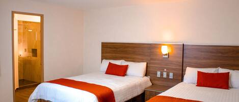 A hotel room with two beds, wooden headboards, and a bright ceiling light.