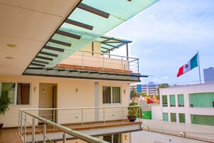 Un bâtiment moderne doté d’un balcon, d’un drapeau et d’un escalier.