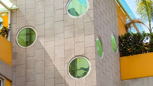 A building with multiple circular windows and a yellow facade. - La Casa del Reloj - Zona de Hospitales (Mexico City)