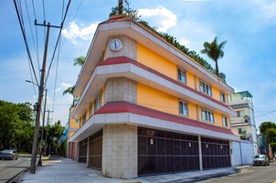 Un immeuble à plusieurs étages, orné d’une horloge sur sa façade, avec un garage et un ciel dégagé.