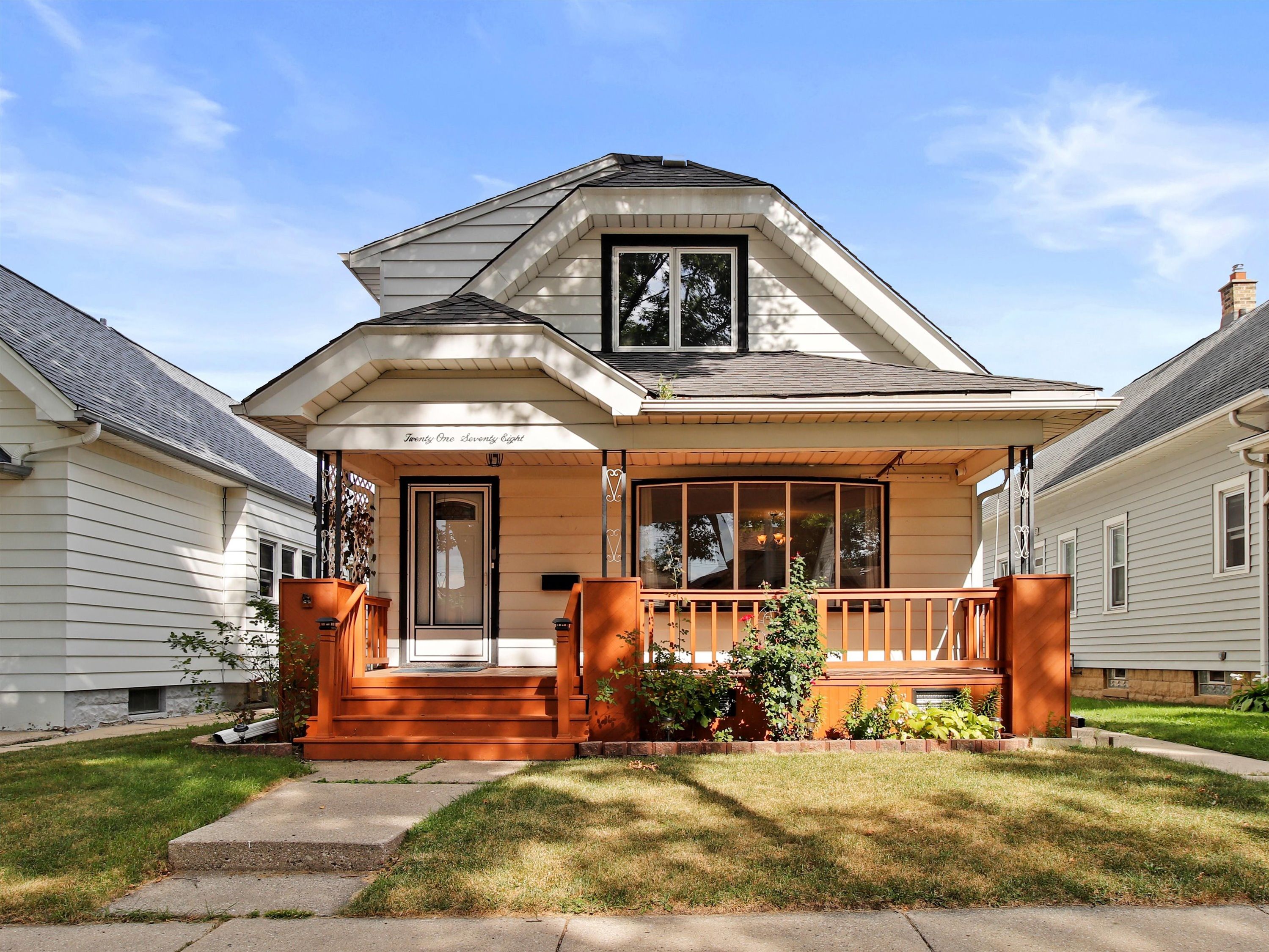 A two-story house with a porch, a front door, and a large window.