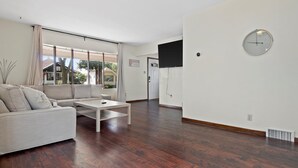 Una sala moderna con sofá, una mesa de centro y un televisor de pantalla plana montado en la pared.