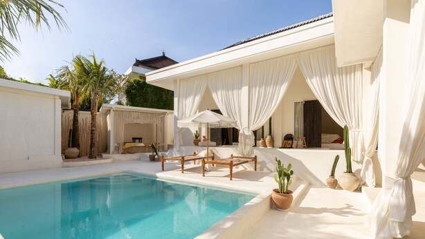 A pool area with a clear blue pool, white curtains, and a few lounge chairs. - Villa Ores Bali (Canggu)