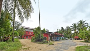 Un edifici vermell amb un rètol que diu "RABI MINI MARKET" i un camí rural al davant.