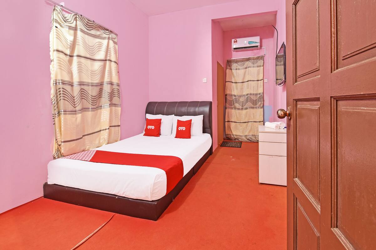 A bedroom with a bed, a bedside table, a wardrobe, and an air conditioning unit.