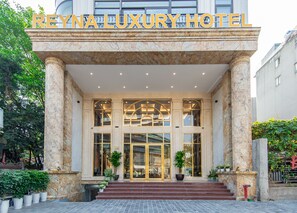 The exterior of Reynaluxury Hotel with marble columns, large glass doors, and potted plants. - Reyna Luxury Hotel by 22Land (Hanoi)