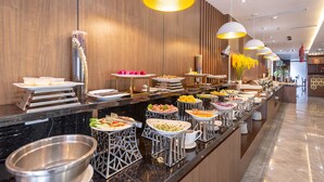 Disposição de buffet com diferentes estações de comida e design de interiores moderno.