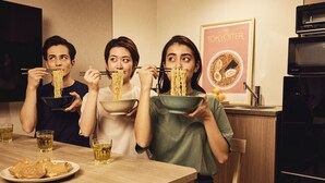 Three people eating noodles at a wooden table with glasses of beer and a plate of pancakes. - Section L Hatchobori (Tokyo)