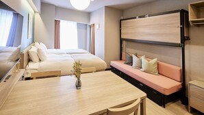 A hotel room with a bed, a sofa, a table with a vase, and a wardrobe. - Section L Hatchobori (Tokyo)