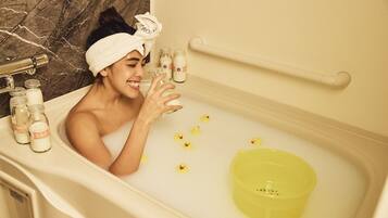 A bathtub with a yellow basin, bottles of milk, and rubber ducks.