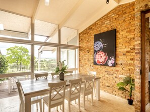 A dining area with a brick wall, a large window, and a table with chairs. - Mars: The Menangle Hideaway: Relax and Unwin (Menangle)