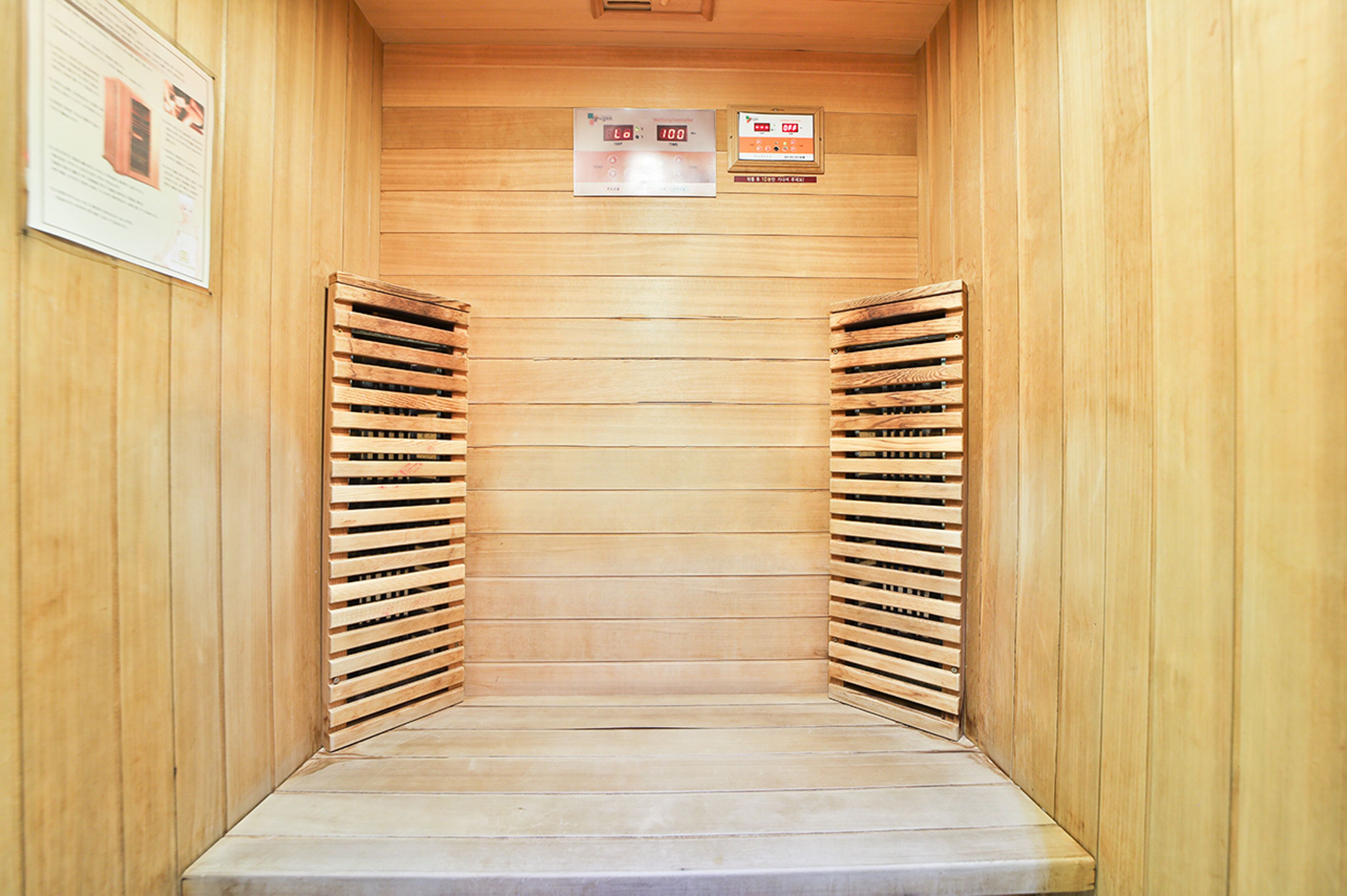 Una sauna con paredes y bancos de madera, un panel de control y carteles informativos.