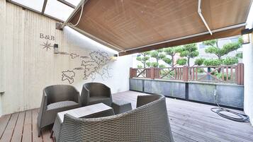 Un espacio al aire libre con mobiliario de mimbre, una terraza de madera y una pared con un mapa y el logotipo de B&B.